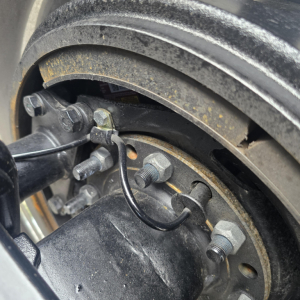 Wheel hub and lug nuts on a Mack PI64T drive tire assembly showing the rotor and brake components.