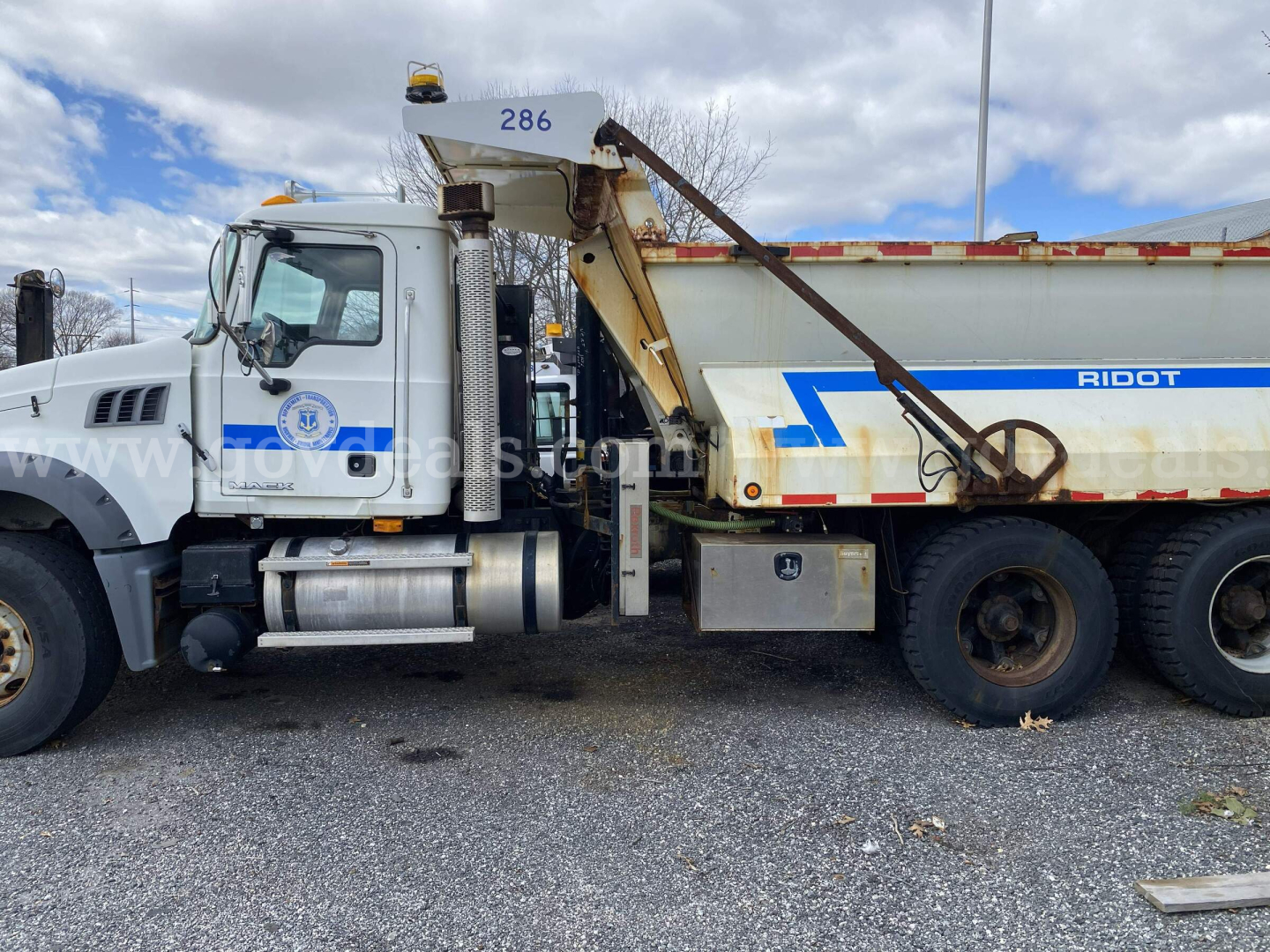 Truck front cab and dump bed showing Mack GU713 with RIDOT decal and hydraulic system