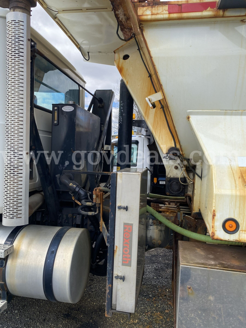 Truck cab and chassis of a 2010 Mack GU713 dump truck showing hydraulic lines and control box