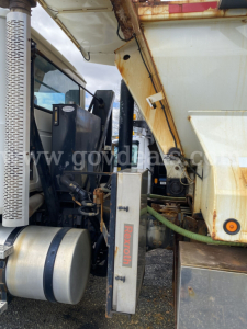 Truck cab and chassis of a 2010 Mack GU713 dump truck showing hydraulic lines and control box