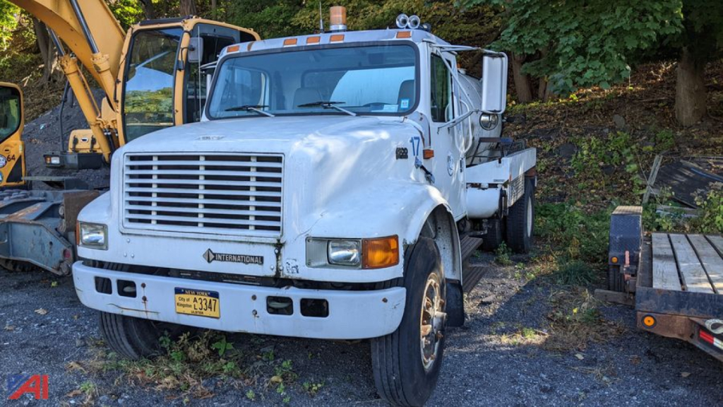 International 4900 sewer jet truck showing front with grille, headlights, bumper, and mounted water/tank body in a yard.