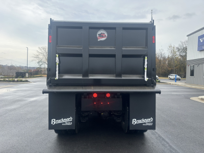Dump truck tail showing rear view of a new Mack GR84F with dual mud flaps, rear lights, and a badge on the tailgate.