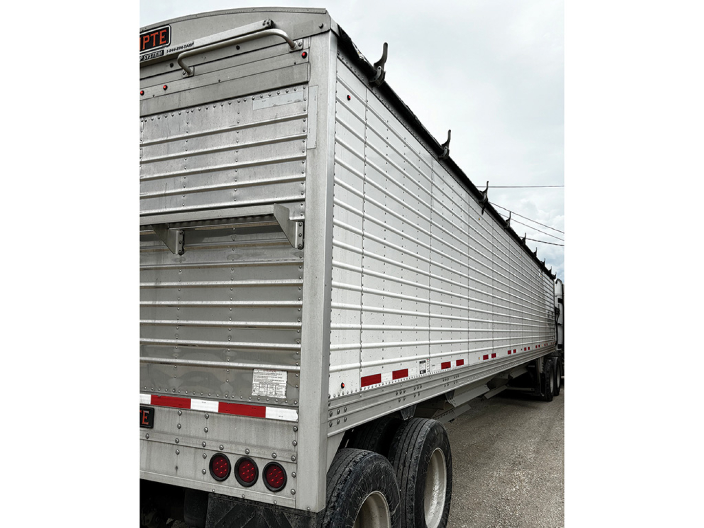Trailer side view showing 2018 Timpte Super Hopper with metal siderails and red reflective tape along bottom edge.