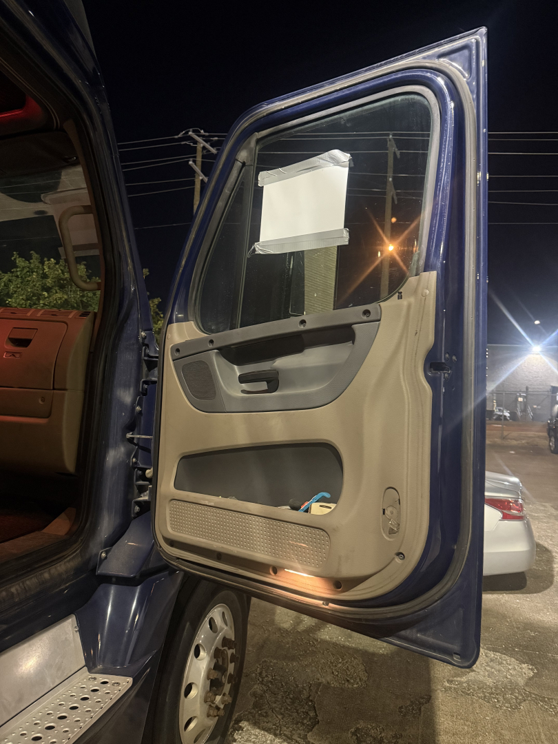 Truck cab door interior panel visible with beige and brown trim, open door showing interior and entry area, Freightliner Cascadia 2015 listing context.