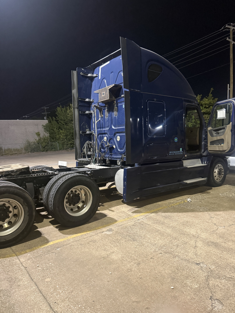 Freightliner Cascadia truck cab side profile showing blue exterior and sleeper area, rear chassis with wheels.