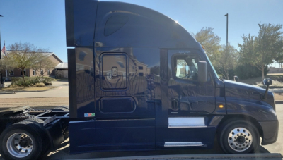 Side view of a blue 2015 Freightliner Cascadia conventional sleeper truck showing the cab and wheel area with chrome accents.