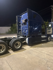 Freightliner Cascadia truck cab side profile showing blue exterior and sleeper area, rear chassis with wheels.