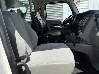 Kenworth T880 cab interior showing driver and passenger seats, steering wheel, dashboard, and gray fabric upholstery.