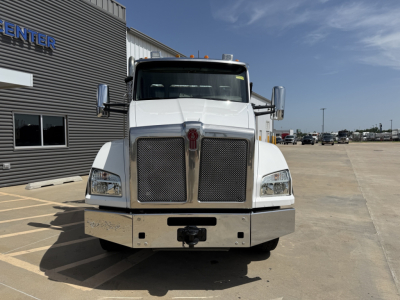 Kenworth T880 front view showing large grille and bumper with diamond-plate chrome; clear windshield, side mirrors, and factory emblem.