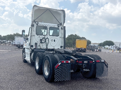 Truck tractor rear view showing Freightliner Cascadia 125 Evolution chassis with 4x4 rear axles and fifth wheel, no trailer attached, white cab with open sleeper compartment.