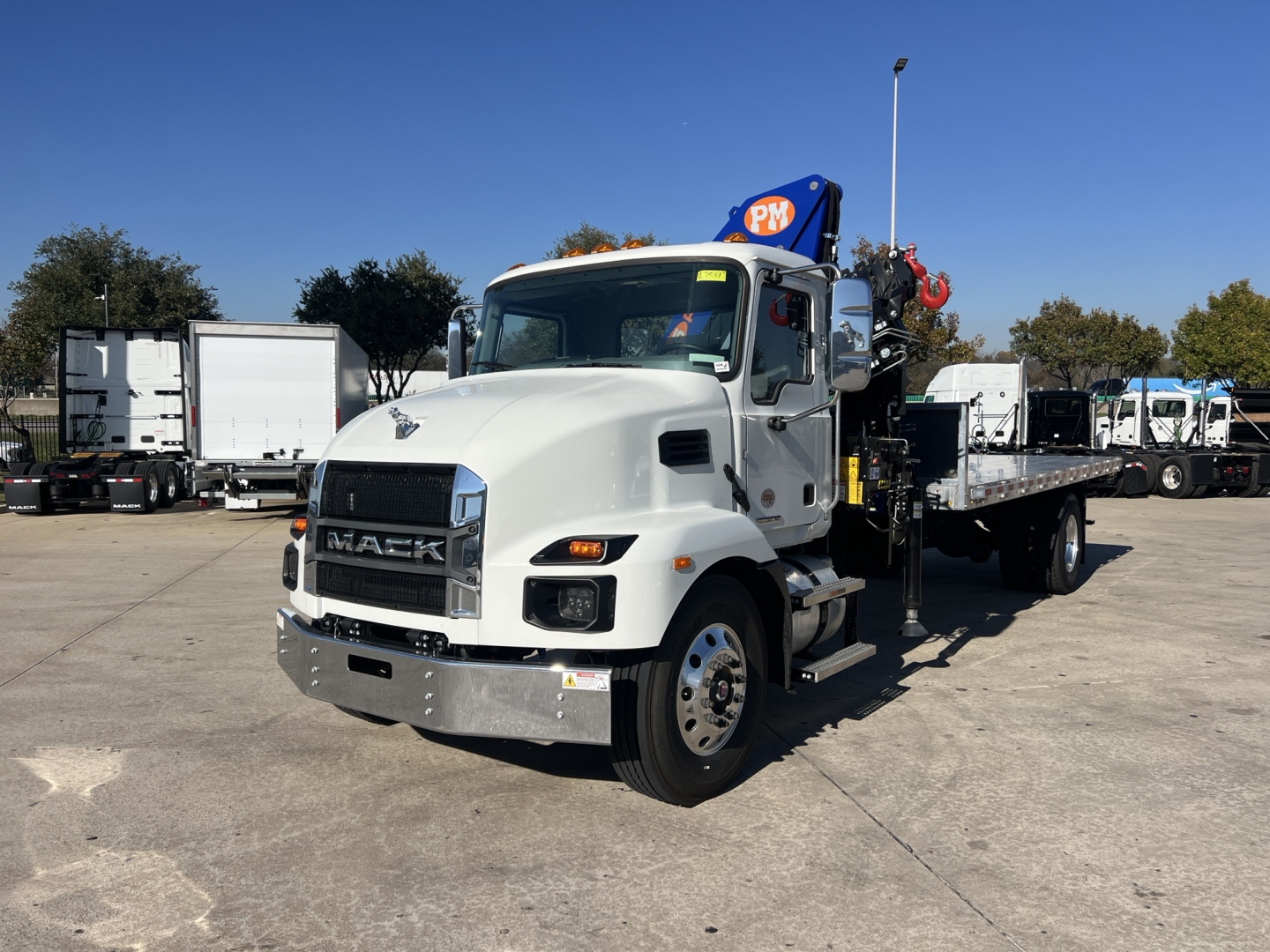 White 2025 Mack MD7 boom truck with crane mounted on flatbed, front grille displays MACK, VIN sticker not visible, no text readable on equipment aside from truck branding.