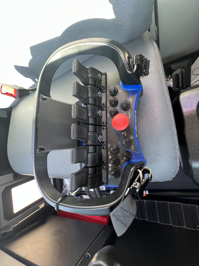 Dashboard control panel with multiple switch banks and a red knob in a Mack MD7 cab. View shows steering area and switch array.