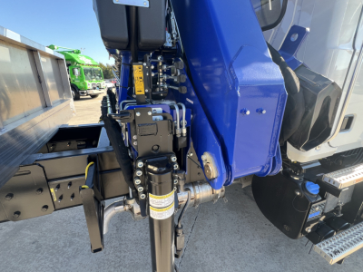 Mack MD7 boom truck side view showing hydraulic crane assembly and black hydraulic cylinder with label, blue boom, and steps.
