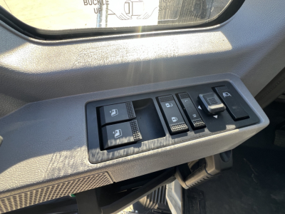 Truck interior door control panel with window switches and mirror controls inside a Mack MD7.