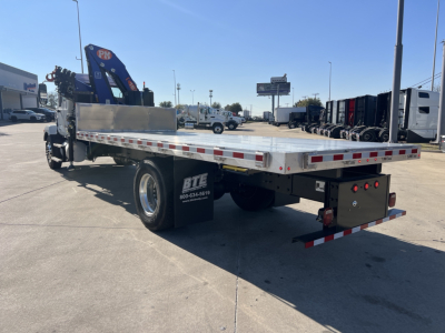 Mack MD7 flatbed tow truck rear view showing aluminum deck with reflective tape and a hydraulic boom crane on the left side.