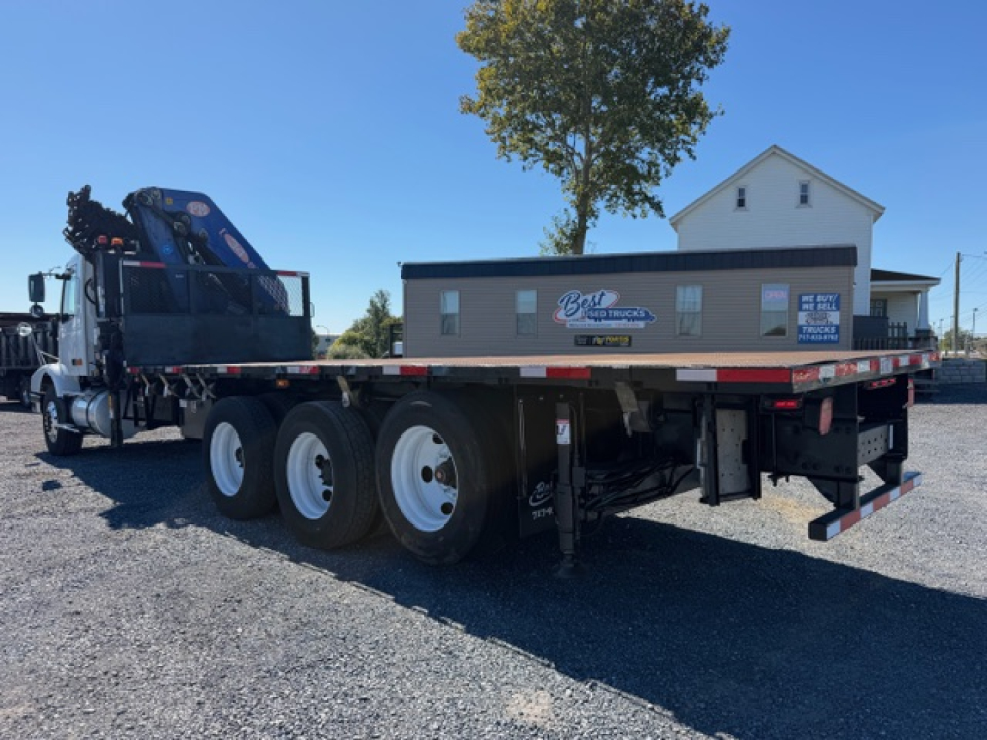 Flatbed tow truck with crane in rear, Volvo VHD 2006, shows triple rear axles, crane mounted on cab area, flatbed and toolbox, VIN 4V5KC9GG66N418582 visible on sticker.