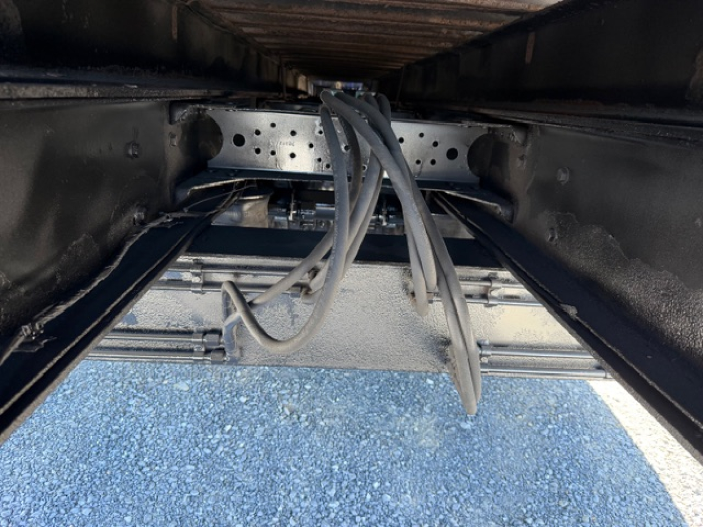 Volvo VHD crane truck undercarriage showing hydraulic hoses and steel frame, view from below.