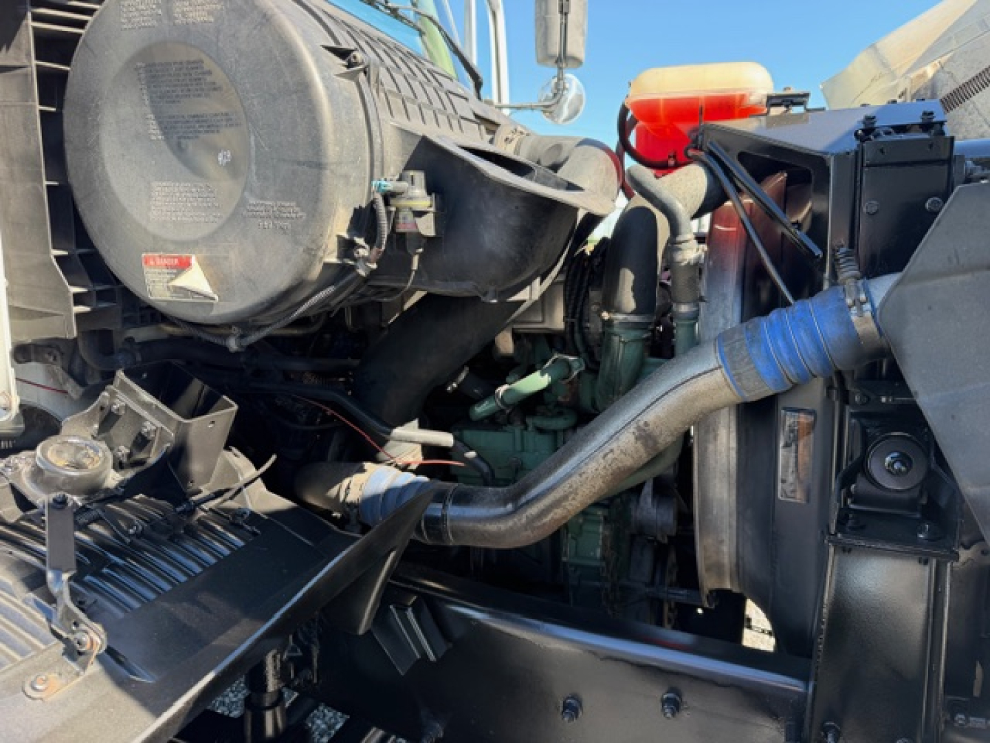 Volvo VHD engine bay showing air intake housing and coolant reservoir with hoses and components.