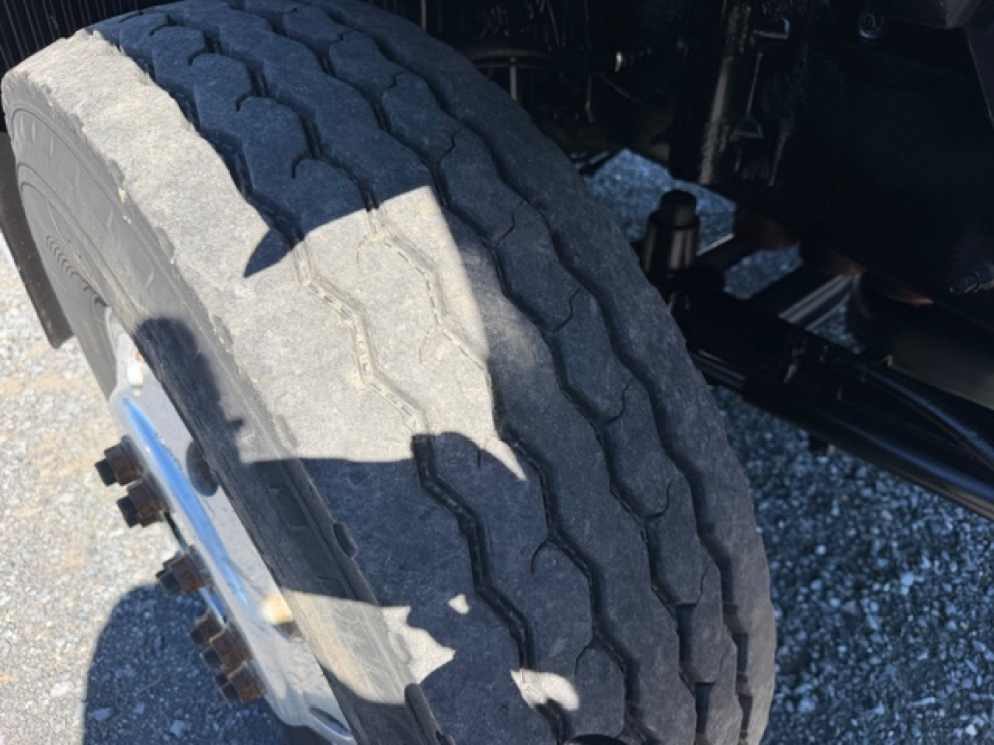 Front wheel and tire of a Volvo VHD crane truck showing dual rear duals and heavy tread with wheel hub and brake components visible.