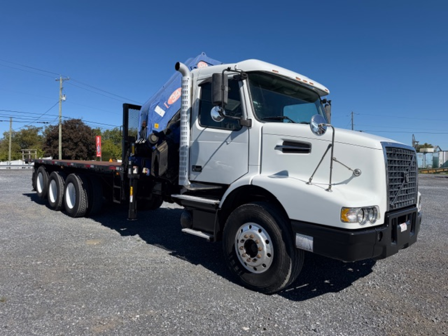 Volvo VHD truck with crane body, front view angled, white cab, blue crane tank, no visible license plate, large tires, side mirrors.