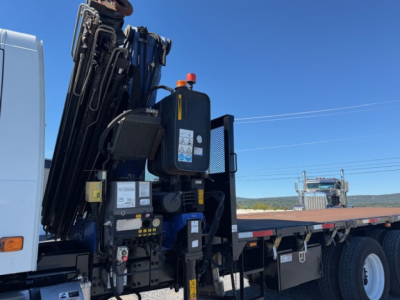 Volvo VHD crane truck side view showing hydraulic crane controls and equipment on flatbed; blue sky background.