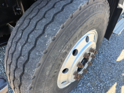 Wheel end of a Volvo VHD truck showing tire tread and steel wheel with lug nuts and hub, trailer/drive axle visible.