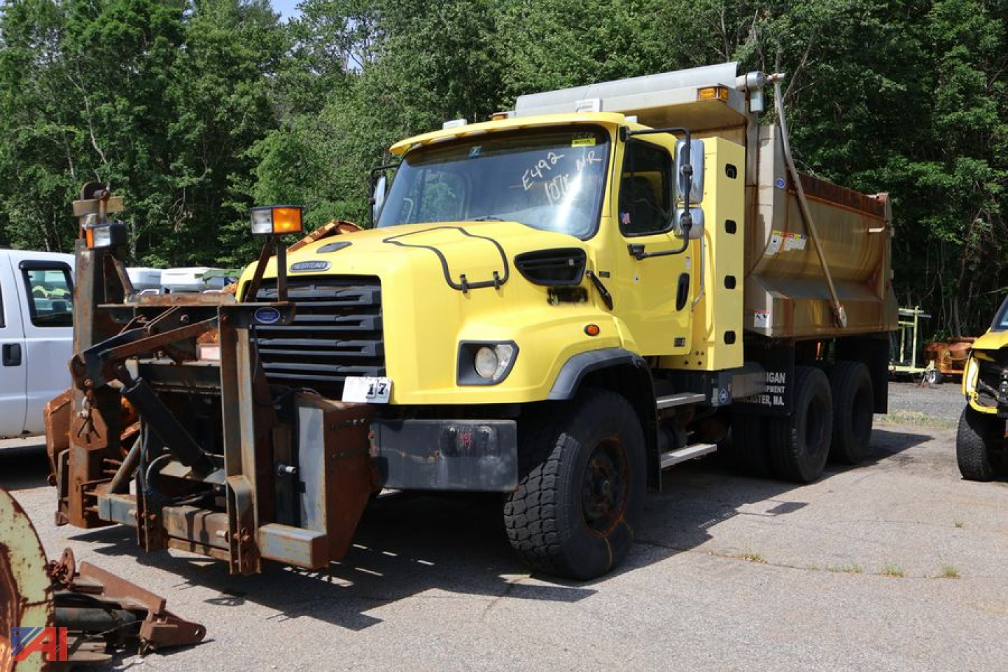 Dump truck with yellow Freightliner 114 SD chassis and plow attachment in front, side view showing sander/plow gear and dumping bed, used condition.