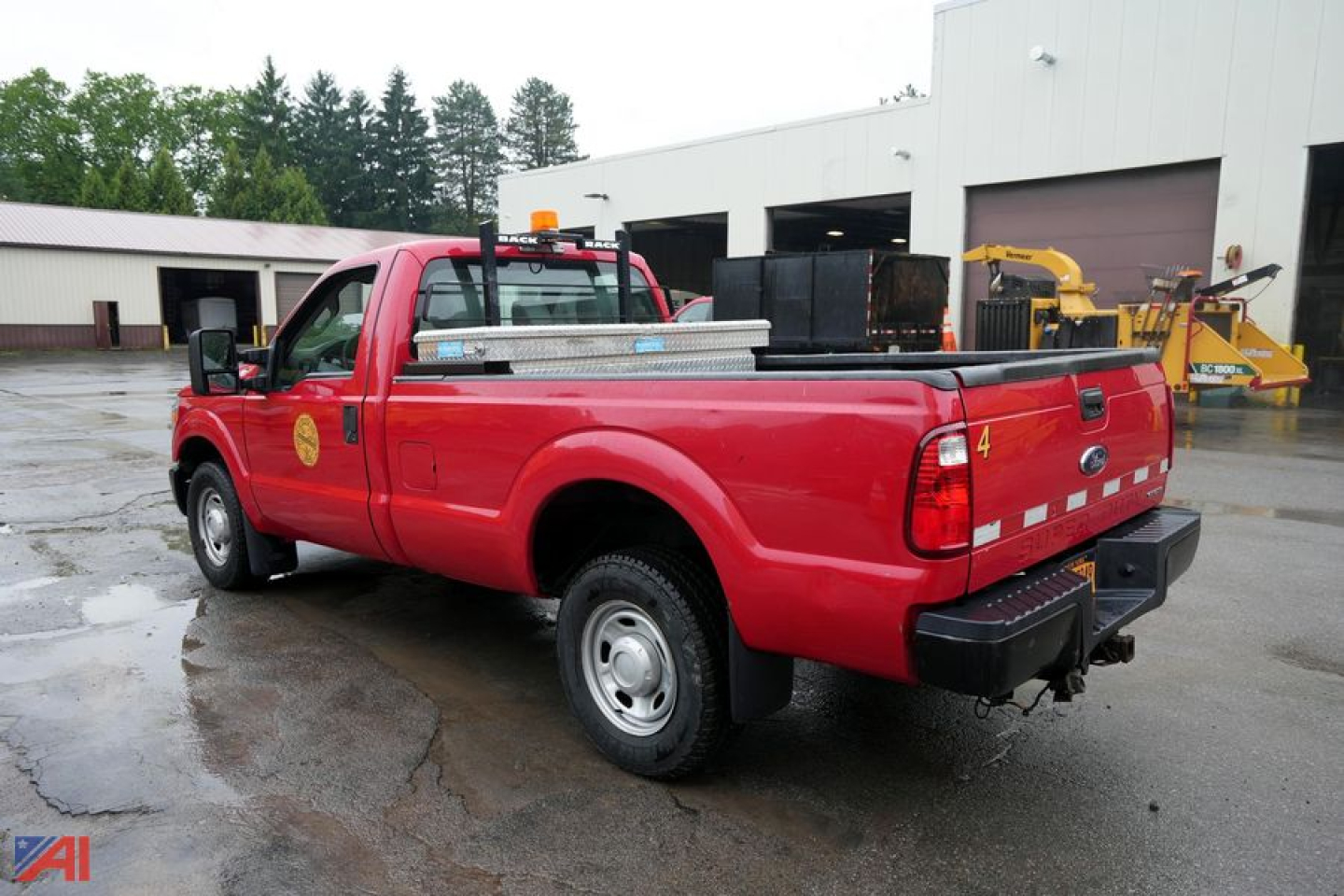 Ford F-250 XL SD pickup truck with toolbox in bed, red exterior, seen from rear-left angle.