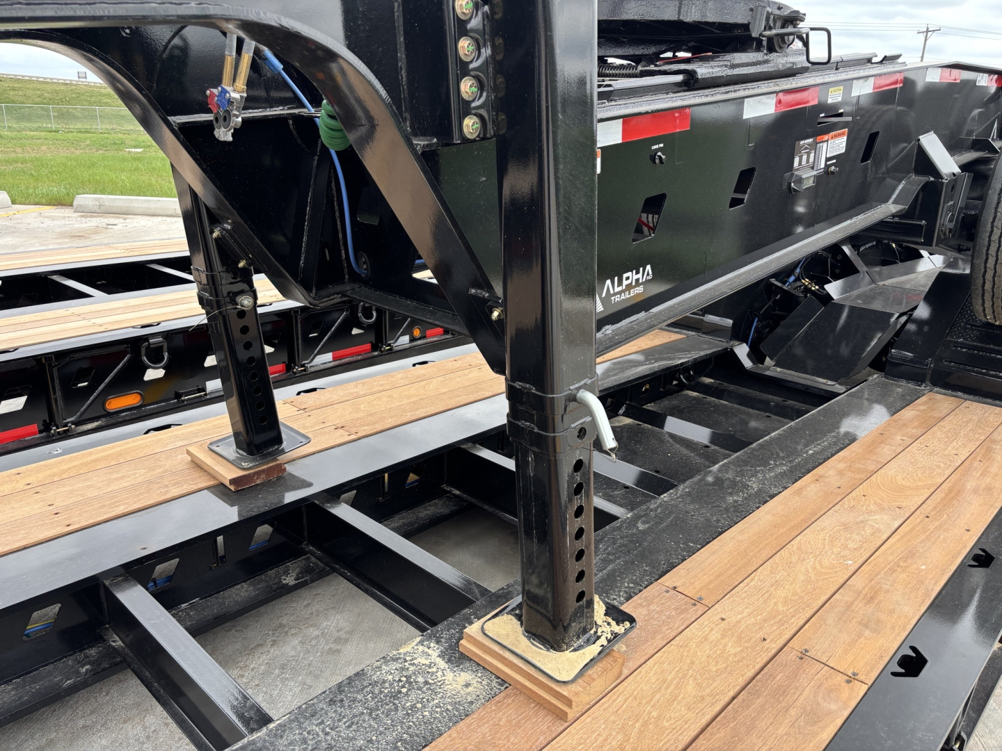 Alpha A80JD Jeep Dolly trailer frame with adjustable legs and wooden deck, showing steel beams and mounting plates.