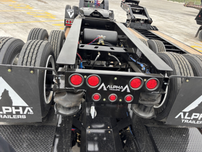 Alpha Trailers Dolly chassis rear view showing dual axle setup, red taillights, and Alpha Trailers branding on mud flaps.