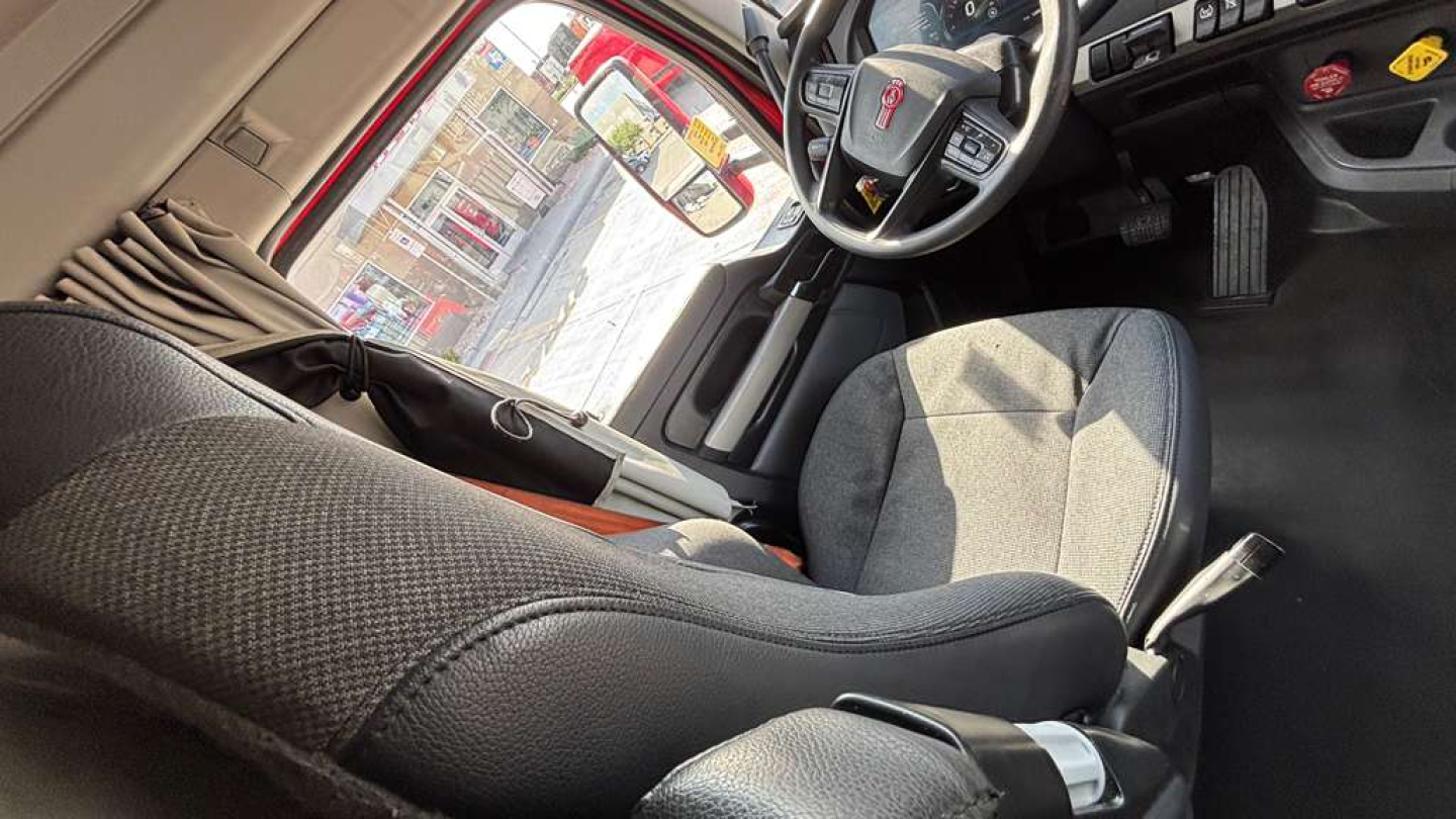 Kenworth T680 cab interior showing driver seat and steering wheel with dashboard view