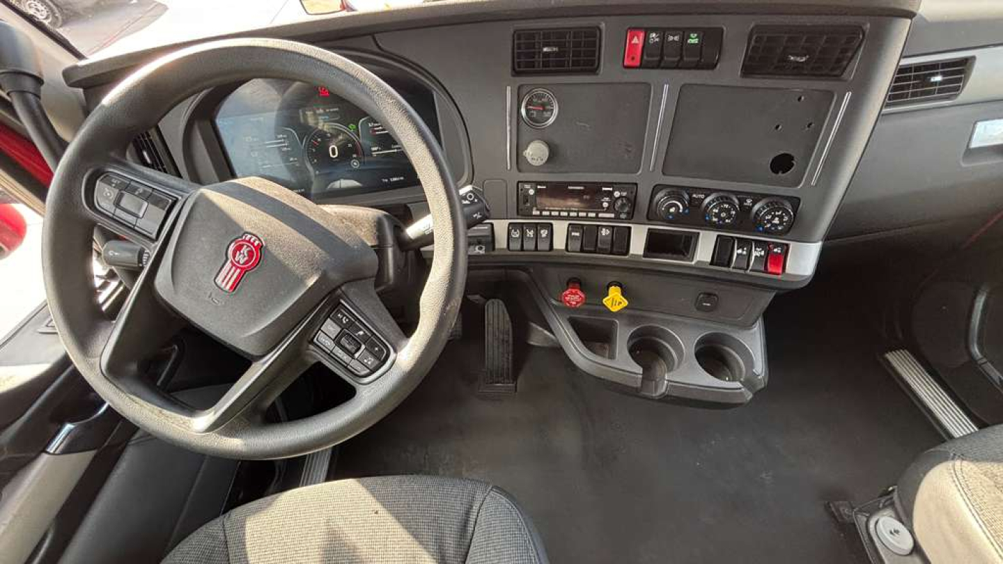 Kenworth T680 cab interior showing steering wheel, dash gauges, and center console controls.