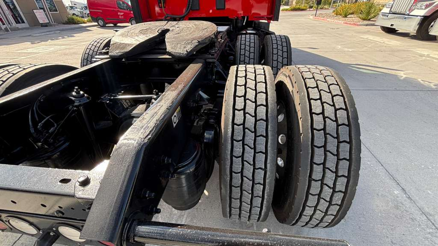 Kenworth T680 chassis with dual rear axles and spare tires, engine bay view showing suspension and frame components.