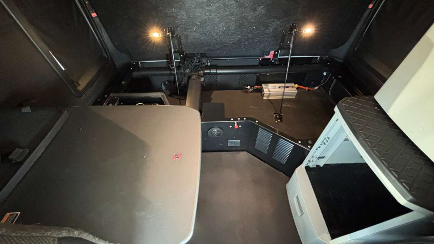 Kenworth T680 interior cab area showing sleeper bunk and dashboard controls with overhead storage.