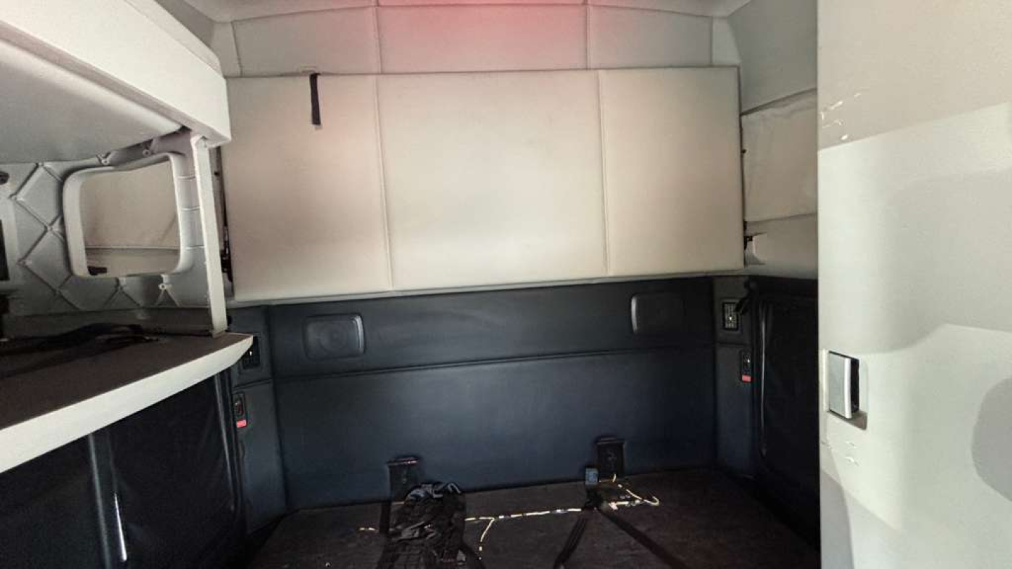 Truck sleeper cab interior showing storage cabinets and bed area with white and gray panels.