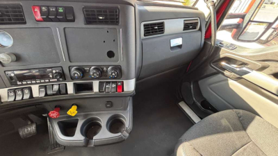 Kenworth T680 cab interior dash area showing center console, gauges, climate controls, steering wheel, and passenger-side door; driver seat visible.