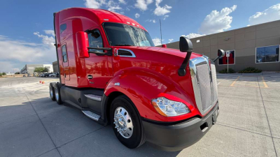 Kenworth T680 truck in red, front three-quarter view showing semi-truck hood, grille, headlight, and side mirrors.