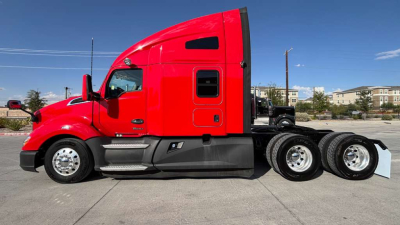 Kenworth T680 sleeper tractor in red profile view showing side cab details and rear wheel area.