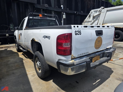Chevrolet Silverado 2500HD pickup truck rear-left view showing 4x4 badge, tailgate, and federal district seal on tailgate with worn bumper and utility bed.