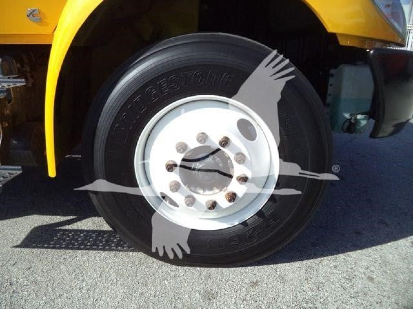 Front wheel of a yellow 2019 International 4300 truck showing Bridgestone tire and white steel wheel with lug nuts.