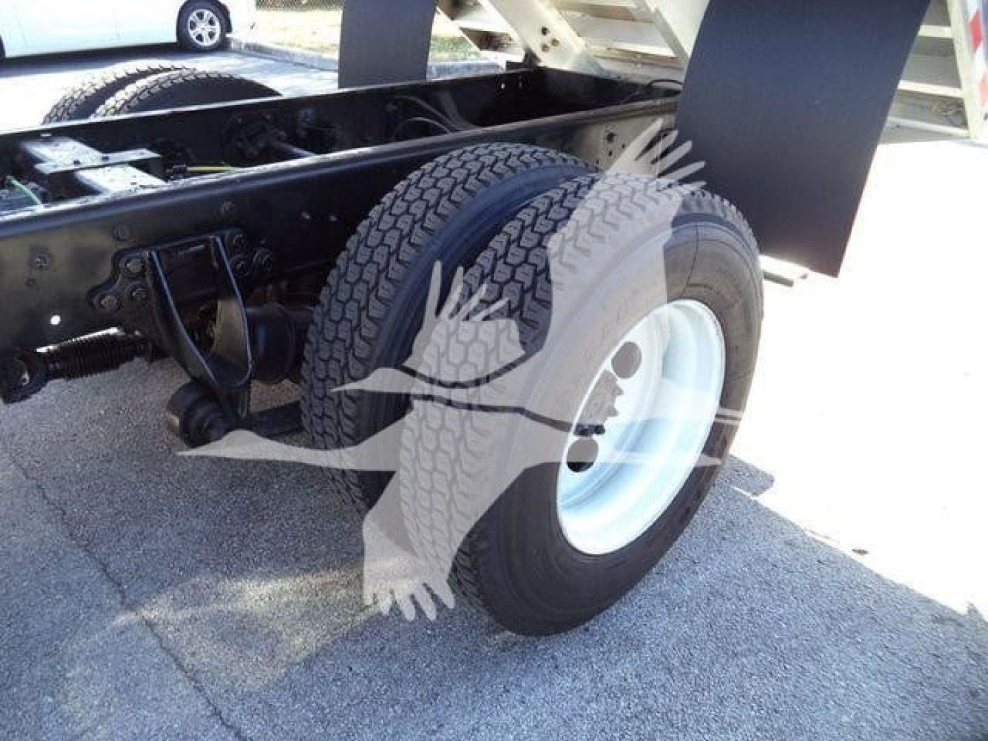 Truck rear wheel area showing dual tires and chassis with black-painted frame; visible components include suspension and undercarriage.
