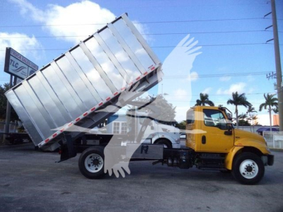 Truck-mounted chipper dump bed on 2019 International 4300 dual-axle chassis with yellow cab and silver refuse body, raised bed tipper in operation.