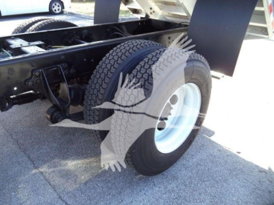 Truck rear wheel area showing dual tires and chassis with black-painted frame; visible components include suspension and undercarriage.