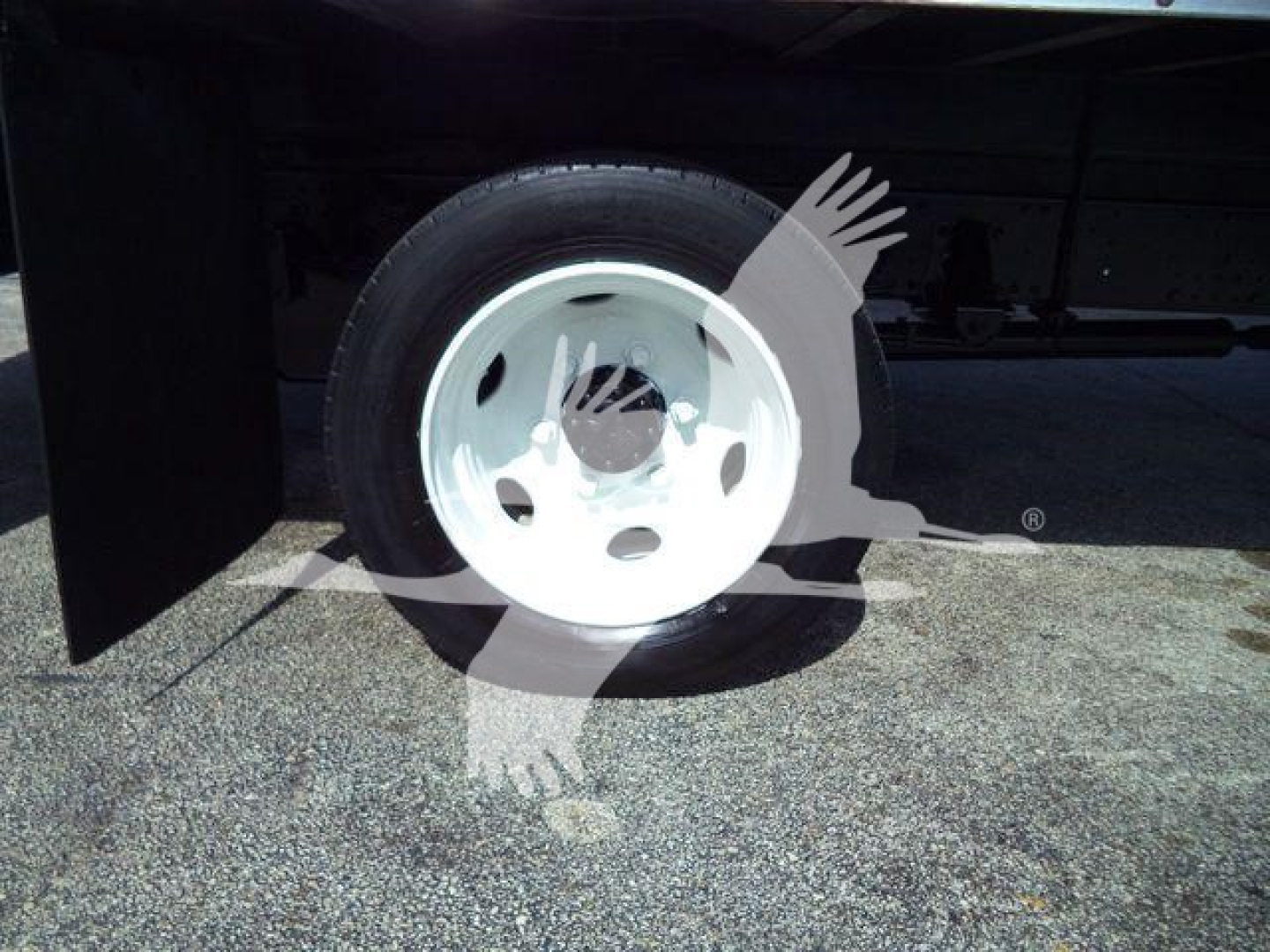 Isuzu NPR/NRR truck wheel and tire visible under a cargo box, white steel rim, partial undercarriage and frame.