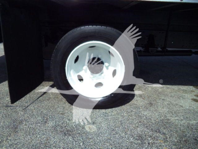 Isuzu NPR/NRR truck wheel and tire visible under a cargo box, white steel rim, partial undercarriage and frame.