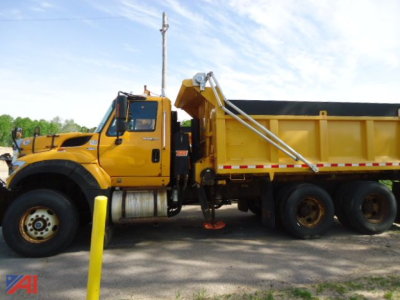 Yellow 2012 International WorkStar 7600 side dump truck with hydraulic spike and dump bed, parked on lot.