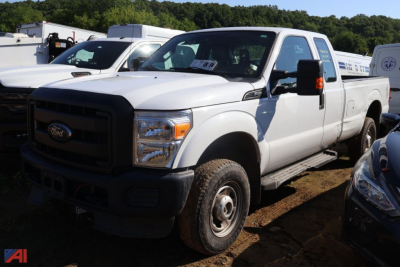 Ford F-250 Super Duty pickup truck in a lot showing front grille with Ford emblem, large headlights, and crew cab; white exterior; steps along side; dirt ground.