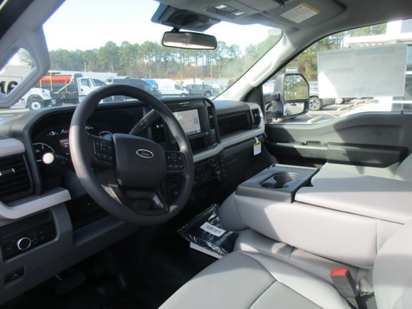 Ford F-450 cab and chassis interior showing steering wheel, dashboard, center console, and light gray seats.
