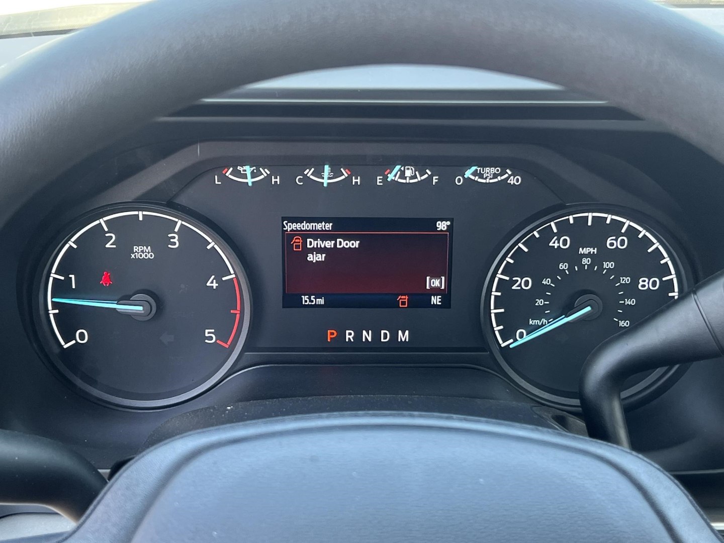Ford F-450 cab and chassis dashboard showing instrument cluster with digital speedometer, gear selector (P R N D M), and message: Driver Door ajar.