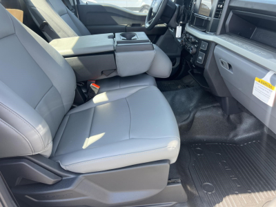 Ford F-450 cab and chassis interior showing front seats, center console, and dashboard with steering wheel; light gray upholstery and clean cabin.